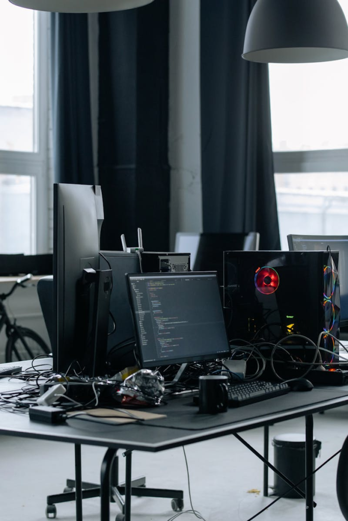 Contemporary workspace featuring computers, coding screens, and office essentials in a tech environment.