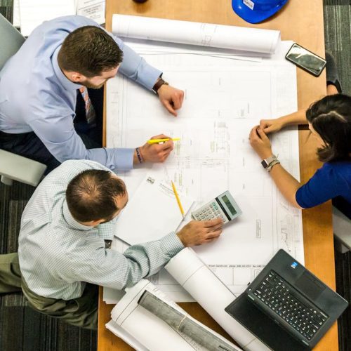 Top view of a team working on construction plans in an office setting.